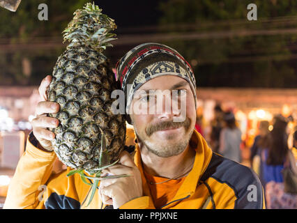 Portrait de l'homme drôle avec beaucoup d'ananas. Banque D'Images