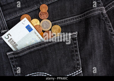 Pièces et billets en euros dans la poche arrière de jeans noir Banque D'Images