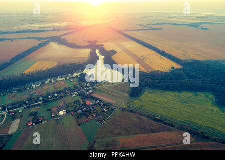 Le lever du soleil sur la campagne environnante. Matin brumeux, paysage rural. Vue aérienne du village, au-dessus au lac, rivière et champs arables Banque D'Images