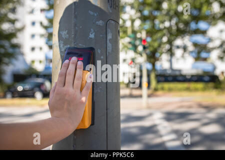 Close-up de la main d'un enfant sur le bouton-poussoir capacitif d'un feu de circulation piétonnière Banque D'Images