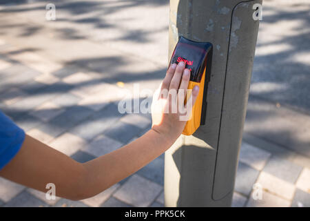 Close-up de la main d'un enfant sur le bouton-poussoir capacitif d'un feu de circulation piétonnière Banque D'Images