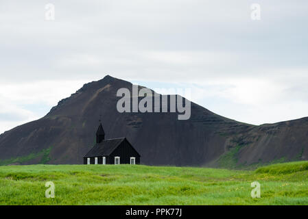 L'église noire dans le village de Budir, Islande. Attraction touristique et religieux. Paysage d'été avec une chapelle et le sommet d'une montagne Banque D'Images