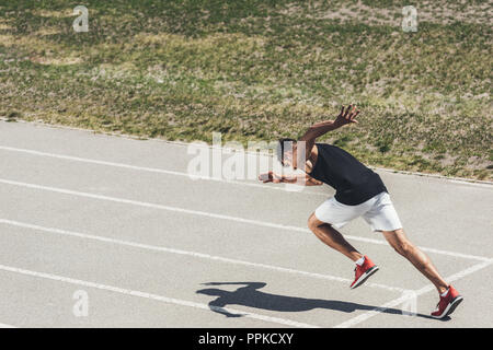 Jeune homme sprinter décollant de position de départ sur une piste de course Banque D'Images