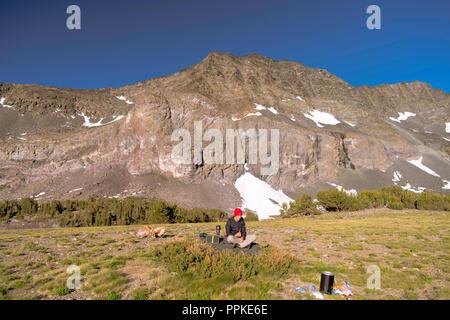 Mange Le petit-déjeuner sur un backpacker rocher près Alger lacs avec Pic Blacktop en arrière-plan ; Ansel Adams Wilderness, Inyo National Forest, la Sierra Nevada Banque D'Images