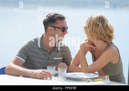 Jeune couple sur la terrasse l'heure du coucher du soleil près de la rivière Banque D'Images