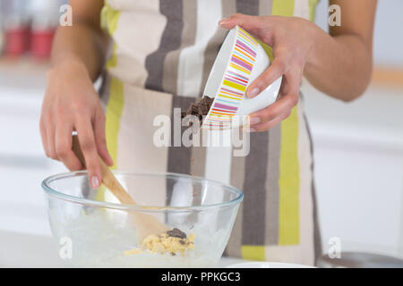 Les mains verser dans un bol de chocolat pour plat délicieux Banque D'Images