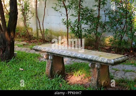 Banc en pierre de style vintage sur le champ de l'herbe verte d'un parc public Banque D'Images