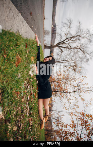 Creative photo d'une fille brune en automne Parc. Woman hanging du bord, allongé sur l'herbe verte. Regarder le monde par le côté Banque D'Images