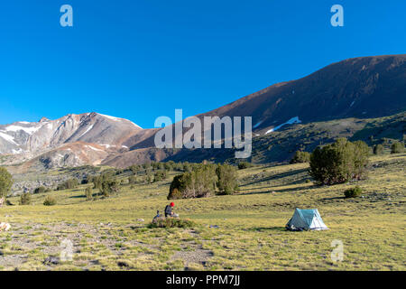 Mange Le petit-déjeuner sur un backpacker rocher près Alger lacs avec Koip Koip Pic et col en arrière-plan ; Ansel Adams Wilderness, Inyo National Forest, Sie Banque D'Images