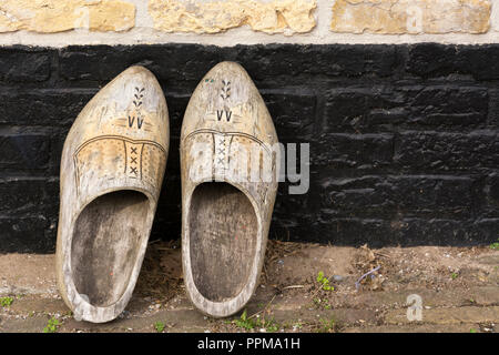 Vue sur une paire de retro vintage traditionnel vieux Néerlandais chaussures en bois décoré, installée sur le mur avant d'entrer dans la maison Banque D'Images