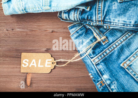 Vente Concept, Vendredi Noir promotions à tag, jeans bleu sur un fond de bois Copyspace. Télévision jeter dessus. Banque D'Images