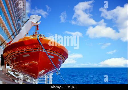 Une embarcation orange suspendues sur une mer bleue sur le côté d'un navire de croisière Banque D'Images