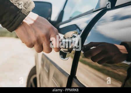 Close-up de la main d'un homme ouvre la porte de la voiture avec une clé. Banque D'Images