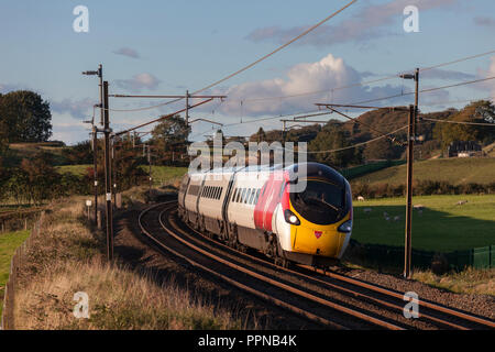 Un Virgin Trains pendolino de la côte ouest sur la ligne principale de la côte ouest dans le Lancashire incliner comme il prend une courbe. Banque D'Images