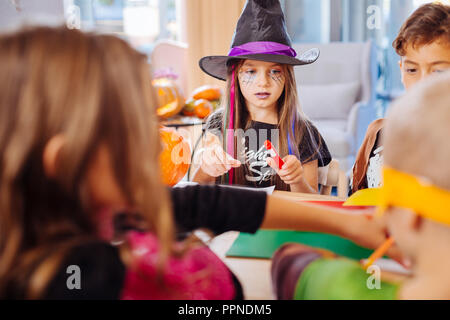 Dark-haired girl wearing black wizard hat pour l'Halloween à jouer avec des amis Banque D'Images