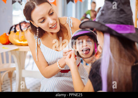 Loving mother holding mirror montrant sa fille maquillage Halloween Banque D'Images