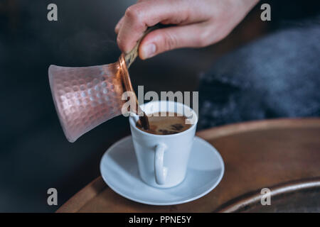 La main de l'homme verse dans une tasse de café Banque D'Images