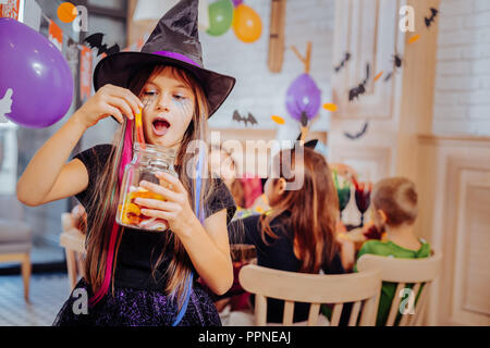 Lycéenne brune portant costume pour Halloween party assistant manger des douceurs Banque D'Images