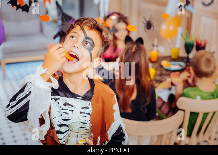 Dark-haired cute boy wearing pirate costume pour Halloween party sentiment amusé Banque D'Images