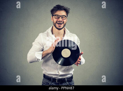 Jeune homme barbe dans les verres holding vintage vinyl record smiling at camera Banque D'Images
