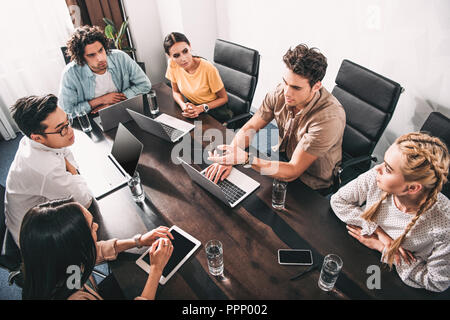 High angle view of multicultural partenaires commerciaux ayant rencontre à table avec les ordinateurs portables de bureau moderne Banque D'Images