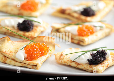 Crêpes avec du caviar rouge et noir sur une plaque Banque D'Images
