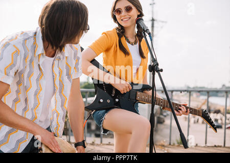 Les jeunes et l'heureux couple de musiciens de rue avec la guitare et le djembé en ville Banque D'Images