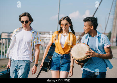 Les jeunes et les professionnels des musiciens de rue transportant des instruments dans la ville Banque D'Images