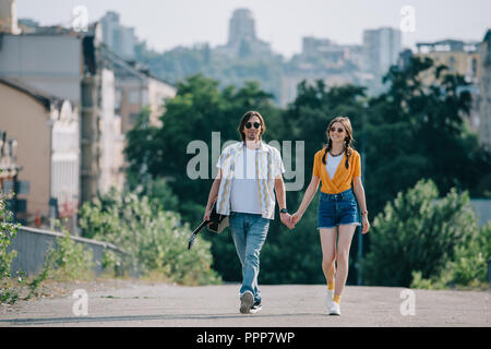 Couple heureux d'amuseurs de hipster walking and holding hands at city street Banque D'Images