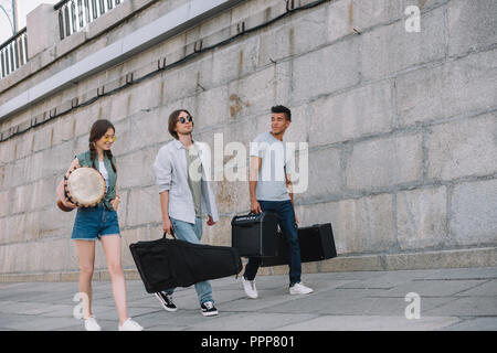 Les jeunes professionnels des amuseurs de la marche et transportant les instruments de musique à city street Banque D'Images