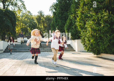 Funny commence. Kids Fashion concept. Le groupe des adolescents et des jeunes filles tournant au parc. Les enfants des vêtements colorés, style de vie, les concepts de couleurs tendance. Banque D'Images