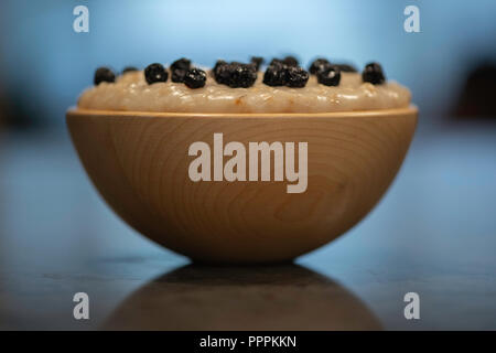 Porridge dans un bol en bois surmontées de bleuets. Banque D'Images