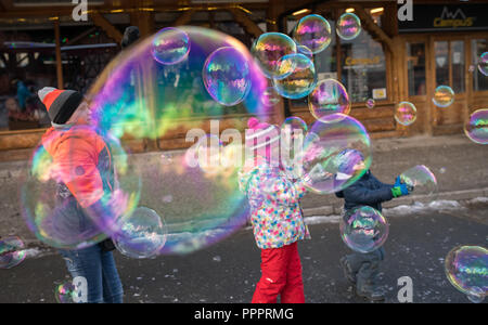 Karpacz, Pologne - Février 2018 : les enfants d'essayer d'attraper les bulles de savon géantes dans la rue principale à Karpacz ville, station de ski d'hiver polonais Banque D'Images