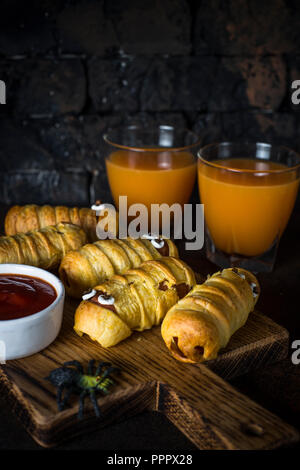 Effrayant et momies saucisses du jus de citrouille sur fond sombre. Banque D'Images