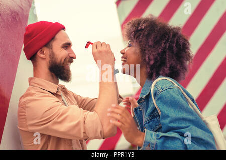 Homme barbu smiling and holding red verres de sa petite amie gaie Banque D'Images