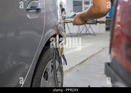 Les mains du mécanicien réparer bosses sur le corps de la voiture avec un dispositif d'aspiration Banque D'Images