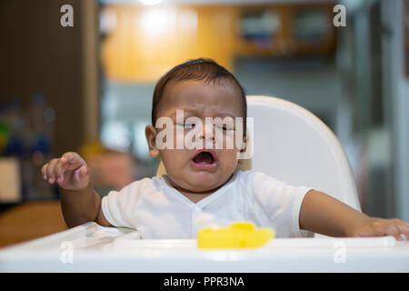 Un bébé qui pleure d'Asie sur chaise. Banque D'Images