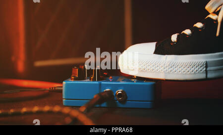 Close up of guitar player pied appuyé sur la pédale. Boucle d'effet de la musique musicien utilise la machine. Dans le quartier branché d'homme sneakers, son pied à jouer sur scène pendant les concerts. Macro-vision Banque D'Images