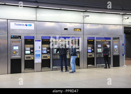 Une banque du libre-service distributeurs automatiques au London's Canary Wharf Underground Station. Montre les clients utilisant des écrans tactiles et des lecteurs de cartes d'huîtres. Banque D'Images