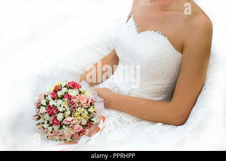 Magnifique bouquet de couleurs différentes dans les mains de la mariée dans une robe de mariée blanche Banque D'Images
