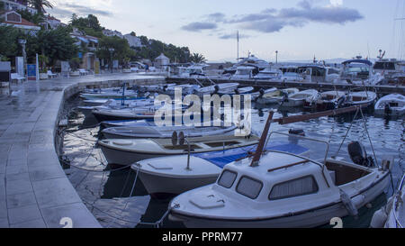 Matin au port croate à Brela. Dans le ciel il y a des nuages éclairés par le soleil levant. Bateaux et yachts sont garées dans le port. Banque D'Images