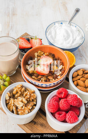 De l'avoine et l'écrou de paléo granola aux fruits servi avec des fruits et des baies, noix de coco, lait yaourt, vertical, selective focus Banque D'Images