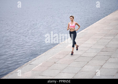 Sérieux au sujet de rester en forme. Vue supérieure de jeunes womanin les vêtements de sport jogging lors de l'exercice en plein air Banque D'Images