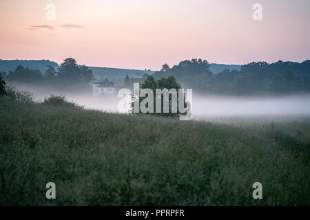 Grand manoir dans le brouillard du matin au lever du soleil. Banque D'Images