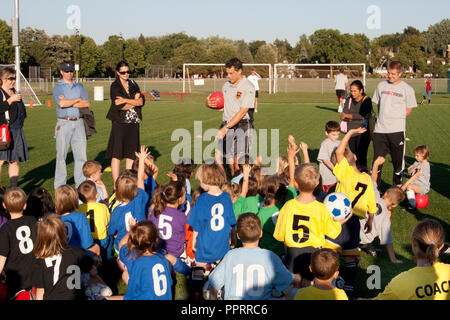 Parler à l'entraîneur, garçons et filles de 7 ans des équipes de football sur le terrain avec les mains levées. St Paul Minnesota MN USA Banque D'Images