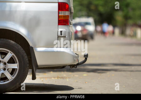 Close-up Vue de côté détail d'argent taille moyenne passager minibus de luxe van avec œillet de barre en stationnement sur la chaussée, rue de la ville ensoleillée d'été brouillée avec sil Banque D'Images