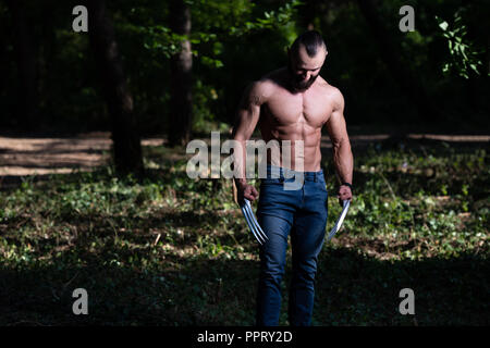 Avec des griffes de superhero Standing Strong Flexing Muscles - Athletic musculaire Fitness Bodybuilder Posing Outdoors Wolverine Banque D'Images