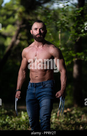 Avec des griffes de superhero Standing Strong Flexing Muscles - Athletic musculaire Fitness Bodybuilder Posing Outdoors Wolverine Banque D'Images