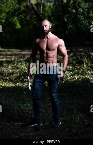 Avec des griffes de superhero Standing Strong Flexing Muscles - Athletic musculaire Fitness Bodybuilder Posing Outdoors Wolverine Banque D'Images