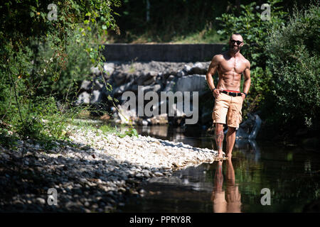 Jeune homme sain Soyons forts Flexing Muscles - Athletic musculaire Fitness Bodybuilder Model Posing Outdoors Banque D'Images